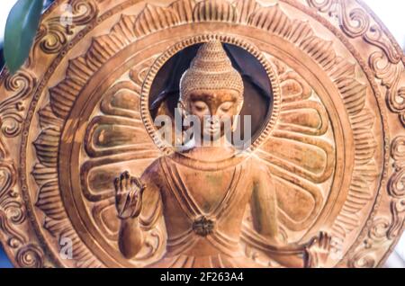 Buddha-Figur auf einem Hintergrund aus Bronzenkreisen. Sakrale Figur im Innenraum. Stockfoto