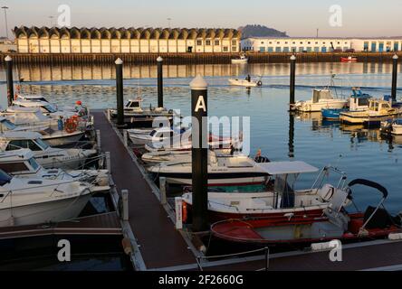 Blick auf kleine Boote, die im Hafengebiet des Maliano Dock festgemacht sind, mit einem kleinen Boot auf dem Weg zum Meer Santander Cantabria Spanien Winter Stockfoto