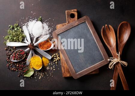 Verschiedene Gewürze Löffel am Steintisch. Draufsicht mit Tafel für Textfreiraum Stockfoto