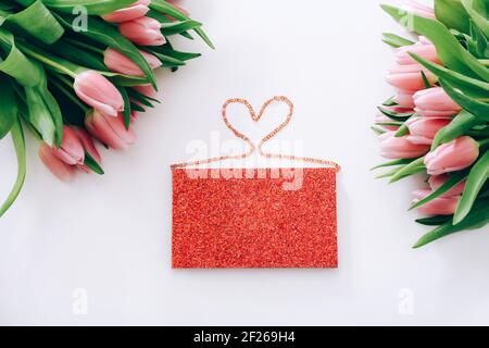 Glitzertasche und schöne rosa Tulpen auf weißem Hintergrund, Draufsicht Stockfoto