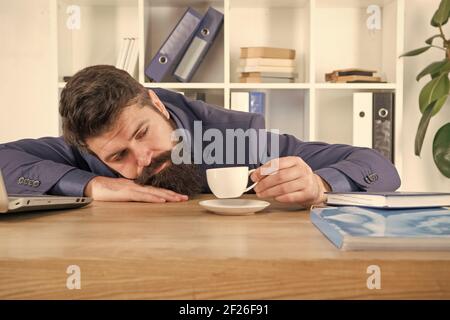 Harter Morgen. Bärtige Hipster formeller Anzug, der sich mit Kaffee entspannt. Büroalltag. Erster Kaffee. Schlaflose Nacht. Zaudern ist Dieb der Zeit. Mann gut aussehend Chef schlafen im Büro Kaffee trinken. Stockfoto