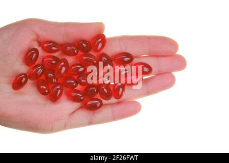 Krillöl-Kapseln. Rote Gelatine Kapseln mit Krillöl in der Hand isoliert auf weißem Hintergrund.Nahrungsergänzungsmittel.gesunde Ernährung. Stockfoto