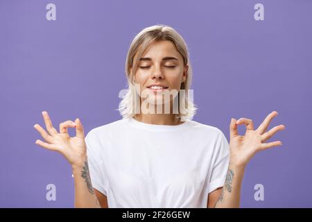 Friedlich ruhig gut aussehende weibliche Blondine in weißem T-Shirt, das die Augen schließt Lächeln erleichtert und glücklich Gefühl zufrieden mit dem Leben st Stockfoto