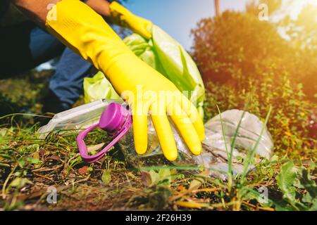 Volunteer in Handschuhen sammeln Müll in Müllbeutel im Freien auf Ein sonniger Tag Stockfoto