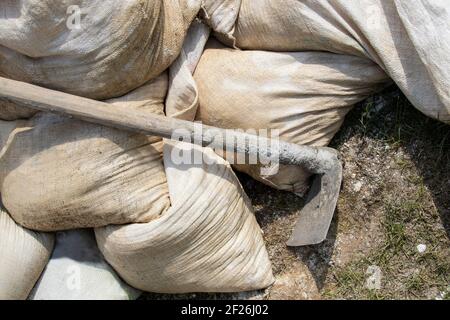 Grundlegende Konstruktion oder Reparatur - Nahaufnahme von Säcken aus Zement Mischen Sie stapelbar und Werkzeug für die Verbreitung es lehnt sich an Sie auf dem Boden Stockfoto