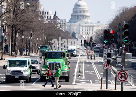 Washington, USA. März 2021, 10th. Die Menschen gehen am 10. März 2021 über eine Straße, die vom US-Kapitolgebäude in Washington, DC, USA, zurückgelassen wurde. Das US-Repräsentantenhaus genehmigte am Mittwoch die endgültige Version des 1,9-Billionen-Dollar-COVID-19-Hilfsgesetzes und schickte es an Präsident Joe Bidens Schreibtisch für seine Unterschrift. Quelle: Liu Jie/Xinhua/Alamy Live News Stockfoto