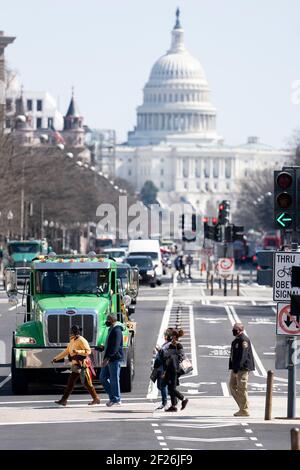 Washington, USA. März 2021, 10th. Die Menschen gehen am 10. März 2021 über eine Straße, die vom US-Kapitolgebäude in Washington, DC, USA, zurückgelassen wurde. Das US-Repräsentantenhaus genehmigte am Mittwoch die endgültige Version des 1,9-Billionen-Dollar-COVID-19-Hilfsgesetzes und schickte es an Präsident Joe Bidens Schreibtisch für seine Unterschrift. Quelle: Liu Jie/Xinhua/Alamy Live News Stockfoto