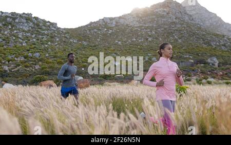 Fit afroamerikanischen Paar in Sportswear durch hohes Gras laufen Stockfoto
