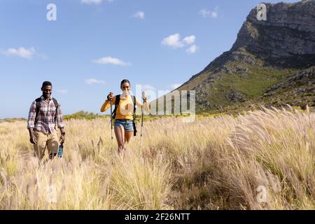 Fit afrcan american paar trägt Rucksäcke nordic Walking mit Stöcken In der Berglandschaft Stockfoto