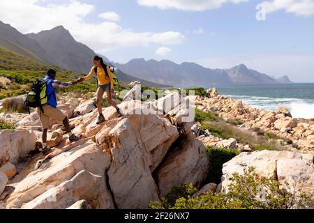 Fit afranamerikanischen Paar trägt Rucksäcke Wandern an der Küste Stockfoto