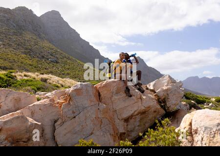 Fit afrcan american paar trägt Rucksack Ruhe Trinkwasser auf Die Küste Stockfoto