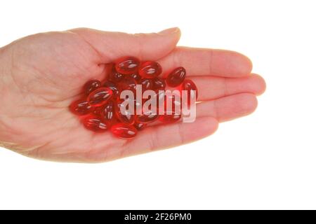 Krillöl-Kapseln. Rote Gelatine Kapseln mit Krillöl in der Hand isoliert auf weißem Hintergrund.Quelle von Omega-Fettsäuren. Ergänzungen.Diät Stockfoto