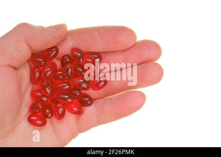 Krillöl-Kapseln. Rote Kapseln mit Krillöl in der Hand isoliert auf weißem Hintergrund.Quelle von Omega-Fettsäuren.Nahaufnahme von Krillöl Stockfoto