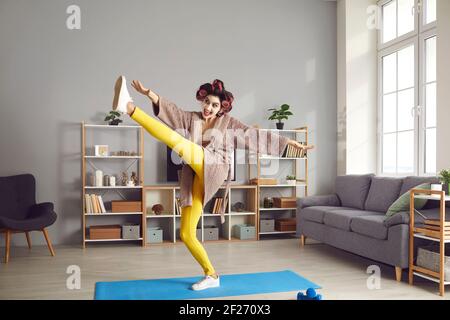 Fröhliche junge Frau genießen Bein Stretching Übung während Fitness-Training Zu Hause Stockfoto