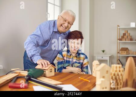 Glücklicher Opa und Enkel machen Holzspielzeug und Spaß haben In der Schreinerei Stockfoto
