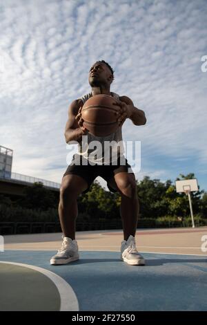 Schwarzer Basketballspieler hockt vor dem Wurf Stockfoto