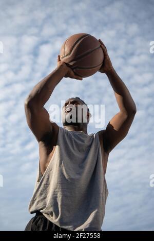 Starke schwarze Basketballspieler werfen Ball Stockfoto