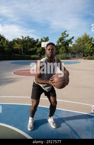 Fokussierter schwarzer Mann spielt Streetball Stockfoto