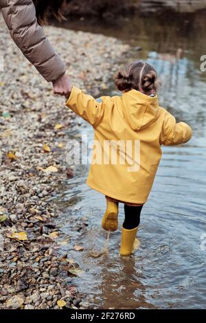 Ein 2-jähriges Mädchen mit ihrer Mutter auf der Bank von Ein Fluss Stockfoto