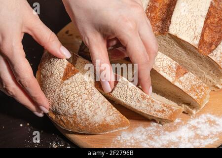 Eine junge Frau Schnitt frisch gebackenes Brot in Scheiben. Gesunde Ernährung. Stockfoto