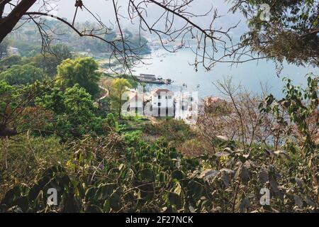 Blick von oben auf die lokale Dorfküste entlang des Atitlan-Sees durch Bäume, San Juan la Laguna, Guatemala Stockfoto