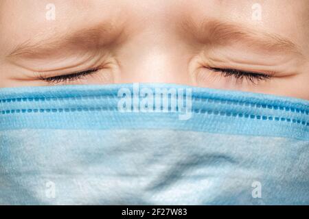 Gesundheitsprobleme Kind geschlossenen Augen Ausdruck. Starke Schmerzen Gesicht Kind Behandlung medizinischer Patient Junge unwohl. Impfung Kind trägt medizinische Maske Stockfoto