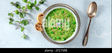 Veganes Suppenpanorama, grüne Creme mit Toast und frischer Minze Stockfoto
