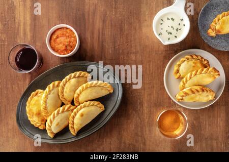 Empanadas mit Saucen und Wein, Schuß von der Oberseite in einem dunklen Holzmöbeln im Landhausstil Hintergrund Stockfoto