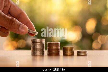 Menschliche Hände halten Münzen und Haufen von Münzen auf Holzboden Finanz-und Investitionsideen. Stockfoto