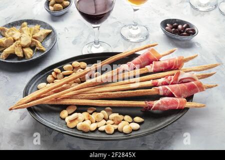 Italienische Antipasti. Grissini, Parmaschinken, Mandeln, Oliven und Wein Stockfoto