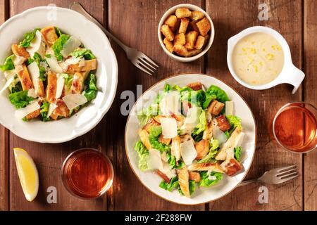 Caesar-Salat, darüber liegende, flache Schüsseln mit Croutons, Sauce und Wein Stockfoto