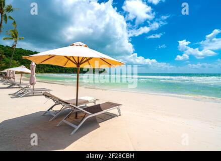 Sonnenliegen unter tropischen Palmen am Strand auf Phu Quoc Insel, Vietnam. Das Lächeln des Strands Stockfoto