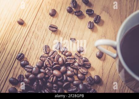Nahaufnahme von frisch gerösteten Kaffeebohnen und Kaffeebecher Auf Holzhintergrund Stockfoto