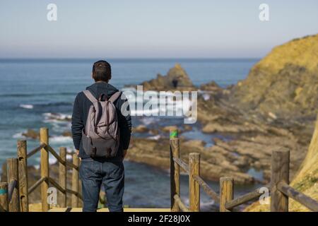 Mann mit Rucksack beim Besuch des Praia dos Machados Strandes in Costa Vicentina, Portugal Stockfoto