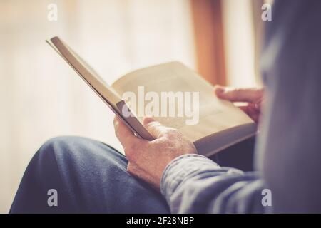 Ein älterer Mann liest zu Hause ein Buch, selektiver Fokus Stockfoto