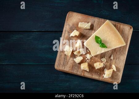 Parmesankäse mit Krümel, von oben auf dunklem Holzhintergrund geschossen Stockfoto