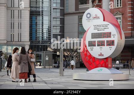Tokio, Japan. März 2021, 10th. Fußgänger, die Gesichtsmasken tragen, um die Ausbreitung von Covid-19 zu verhindern, stehen neben der Countdown-Uhr der Olympischen Spiele 2020 in Tokio, die 135 Tage bis zur offiziellen Eröffnung des Sportereignisses anzeigt. Kredit: SOPA Images Limited/Alamy Live Nachrichten Stockfoto
