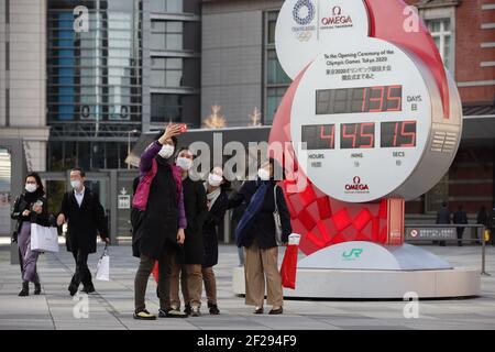 Tokio, Japan. März 2021, 10th. Fußgänger tragen Gesichtsmasken als eine Maßnahme gegen die Ausbreitung von Covid-19 gesehen Selfies neben der Tokyo 2020 Olympischen Spiele Countdown-Uhr zeigt 135 Tage bis zur offiziellen Eröffnung des Sportereignisses. Kredit: SOPA Images Limited/Alamy Live Nachrichten Stockfoto
