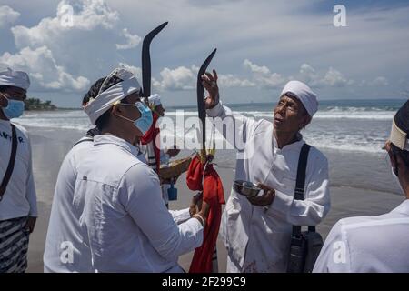 Badung, Bali, Indonesien. März 2021, 10th. Während der Veranstaltung betet ein religiöser Führer auf die Erbliegewaffen. Balinesischer Hindu feiert Melasti, eine seelenreinigende Zeremonie am Petitenget Beach vor Nyepi, dem Tag der Stille, Feiertag. Nyepi wird am 14. März 2021 stattfinden, was das neue Jahr im balinesischen Kalender markiert. Durch den Covid-19 Ausbruch, Melasti in diesem Jahr nur für wenige ausgewählte Menschen begrenzt. Im normalen Zustand gibt es Tausende von ihnen. (Bild: © Dicky BisinglasiZUMA Wire) Stockfoto