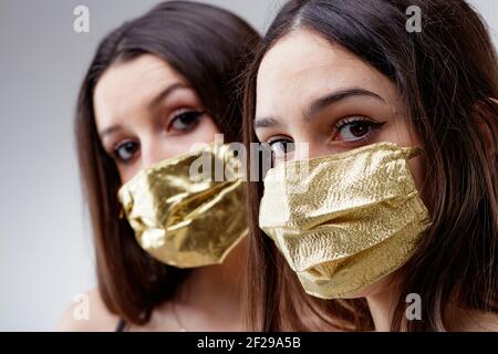 Frauen tragen GOLDENE Schutzmaske Gesicht beobachten Sie, junge Frau gut aussehende und Glück in goldenen Gesichtsbezüge schützen vor COVID-19 Coronavirus Stockfoto