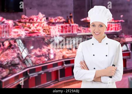 Portrait einer fröhlichen Metzgerin, Ladenbesitzerin oder Köchin mit großem Messer, die auf dem Markt posiert Stockfoto