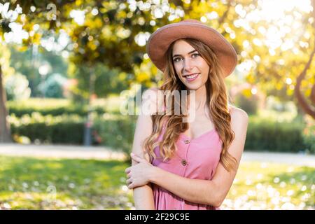 Junge nette Frau lächelt im Park trägt eine süße Niedliches Kleid und Hut an einem Sommertag Stockfoto