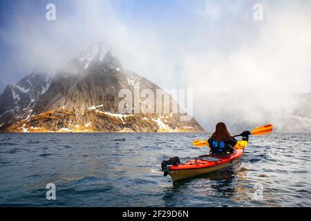 Kajakfahren in reine, Moskenes, Moskenesøya Island, Lofoten Islands, Norwegen. Landschaft mit dem Berg Olstinden. Stockfoto