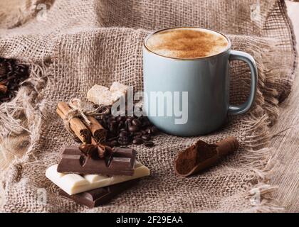tasse Kaffee, Schokolade, Bohnen, Anis und Zimt auf Holzgrund Stockfoto