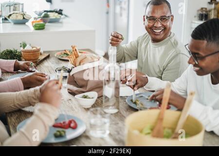 Glückliche schwarze Familie Essen Mittagessen zu Hause - Vater, Tochter, Sohn und Mutter Spaß zusammen am Esstisch sitzen - Schwerpunkt auf Mann Gesicht