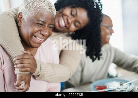 Afrikanische Tochter umarmt ihre Mutter während des Mittagessens zu Hause - Liebe und Familienkonzept - Schwerpunkt Senioren Frauengesicht Stockfoto