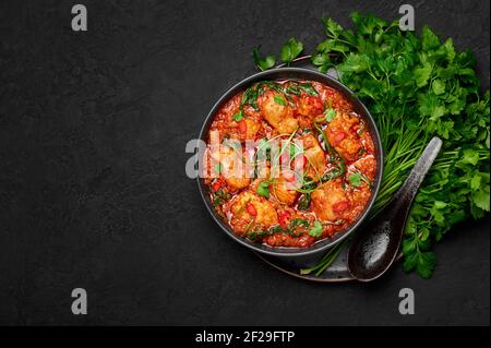 Huhn Vindaloo mit Spinat in schwarzer Schale auf dunkler Schieferplatte. Indische Küche Fleisch Chili Curry Gericht. Authentisches asiatisches Essen. Draufsicht. Speicherplatz kopieren Stockfoto