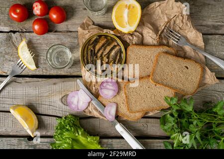 Sandwich mit geräucherten Sprossen in Öl mit Tomaten, Zitrone, Kräutern und Wodka auf Holztisch. Stockfoto