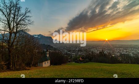 Schöner Sonnenuntergang und Nachglühen in Dornbirn mit Wolken, die auf die Rhomberkapelle zeigen, farbiger Himmel über Rheintal, Staufenspitze, Säntis Stockfoto