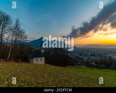 Schöner Sonnenuntergang und Nachglühen in Dornbirn mit Wolken, die auf die Rhomberkapelle zeigen, farbiger Himmel über Rheintal, Staufenspitze, Säntis Stockfoto